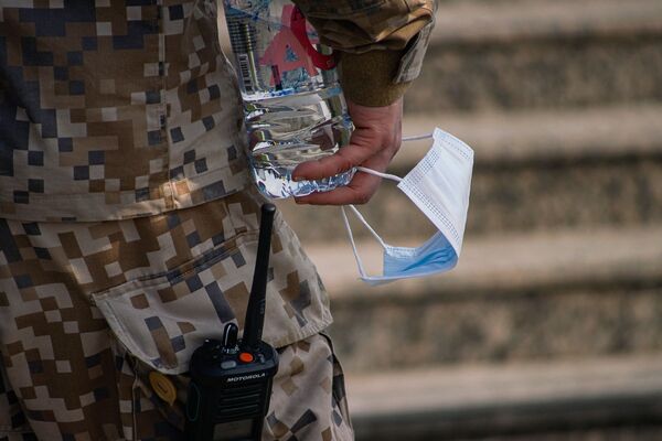 Маска в руке военного, охраняющего центр массовой вакцинации. - Sputnik Латвия