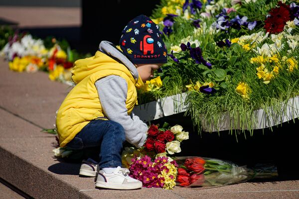 Ребенок с розами в цветах латвийского флага у памятника Свободы в День восстановления независимости Латвии - Sputnik Латвия