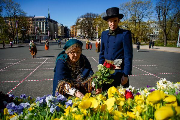 Женщина и мужчина в национальных костюмах принесли цветы к памятнику Свободы в День восстановления независимости Латвии - Sputnik Латвия