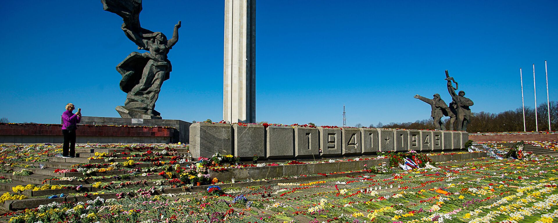 Женщина фотографирует цветы, разложенные у памятника Освободителям Риги - Sputnik Латвия, 1920, 18.06.2021