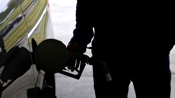 Водитель наполняет бензином бак автомобиля. В США  резко вырос спрос на топливо после кибератаки, которая повредила Колониальный трубопровод в Дареме, штат Северная Каролина - Sputnik Латвия