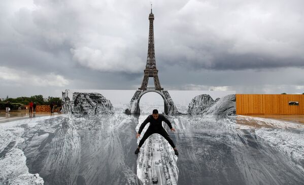 Мужчина позирует на гигантском произведении французского художника JR, установленном на площади Трокадеро перед Эйфелевой башней в Париже, 19 мая 2021 года. - Sputnik Латвия