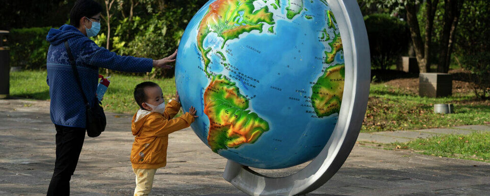 Женщина и ребенок у глобуса в китайском городе Ухань - Sputnik Латвия, 1920, 07.09.2022