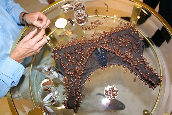 Шоколатье Анри Леру пришивает шоколадные жемчужины на бюстье, предназначенное для ношения поверх платья, во время примерки с актрисой Габриель Лазюр в Париже, 31 октября 2001 года. - Sputnik Латвия