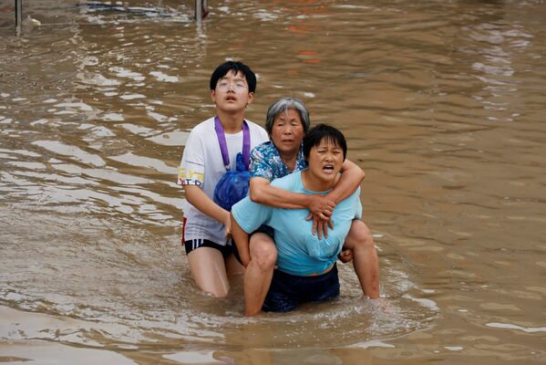 Sieviete nes savu māti pēc lietavu radītajiem plūdiem Džendžou, Henaņas province, Ķīna - Sputnik Latvija