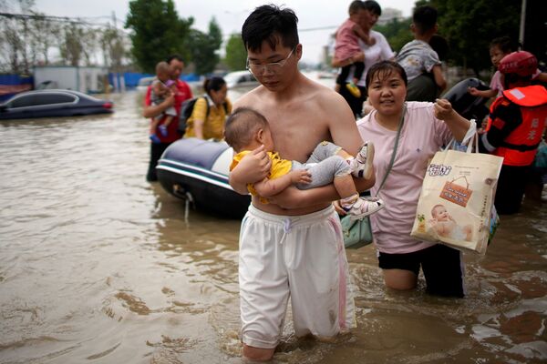 Мужчина с младенцем на руках в затопленном после проливного дождя Чжэнчжоу, провинция Хэнань, Китай - Sputnik Латвия