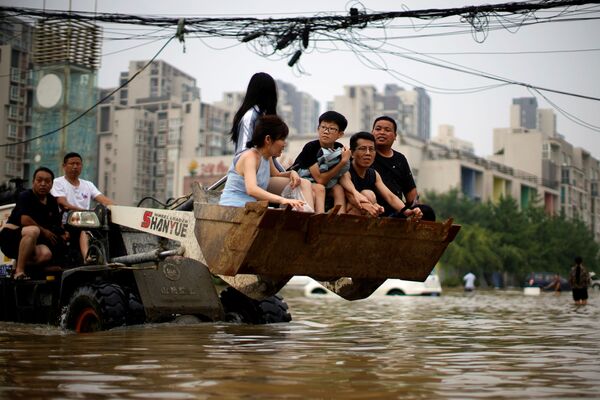 Люди в ковше погрузчика в затопленном проливными дождями Чжэнчжоу, провинция Хэнань, Китай - Sputnik Латвия