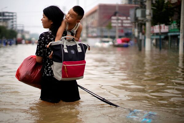 Женщина с ребенком и вещами пробирается по затопленному Чжэнчжоу, провинция Хэнань, Китай - Sputnik Латвия