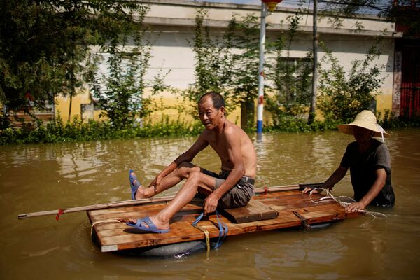 Жители перемещаются по затопленной проливными дождями деревне в Синьсяне, провинция Хэнань, Китай - Sputnik Латвия