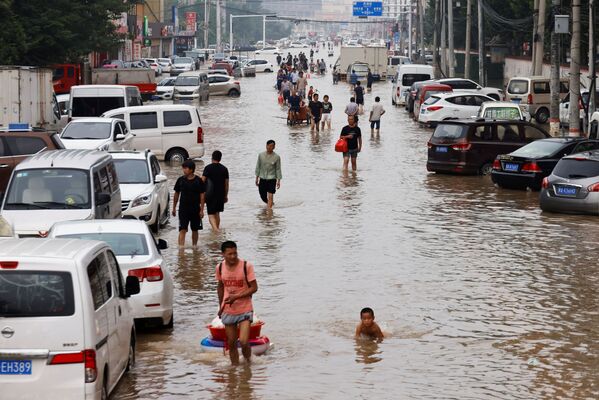 Люди идут по затопленному после проливных дождей Чжэнчжоу, провинция Хэнань, Китай - Sputnik Латвия