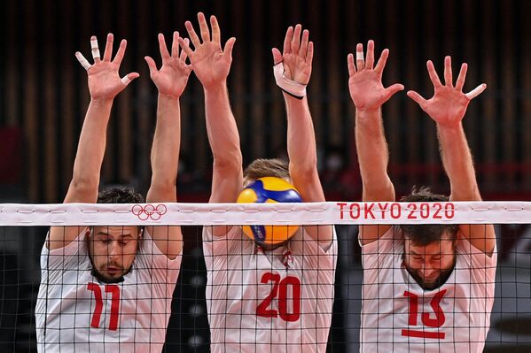 Польские волейболисты Фабиан Држизга, Матеуш Бениек и Михал Кубяк пытаются заблокировать удар во время матча с Венесуэлой. - Sputnik Латвия