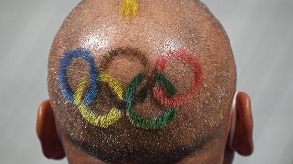 Олимпийские кольца на голове тренера одной из участниц соревнований по стрельбе на Олимпиаде в Токио - Sputnik Латвия