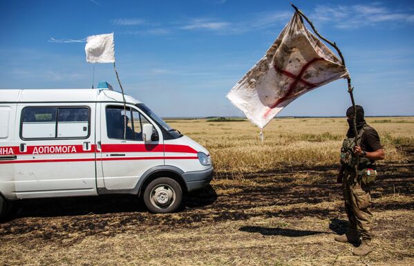 Ukrainas kareivis ar baltu karogu nogalināto nodošanas laikā neitrālajā teritorijā netālu no Dibrovo ciema pie Krievijas un Ukrainas robežas Doņeckas apgabalā - Sputnik Latvija