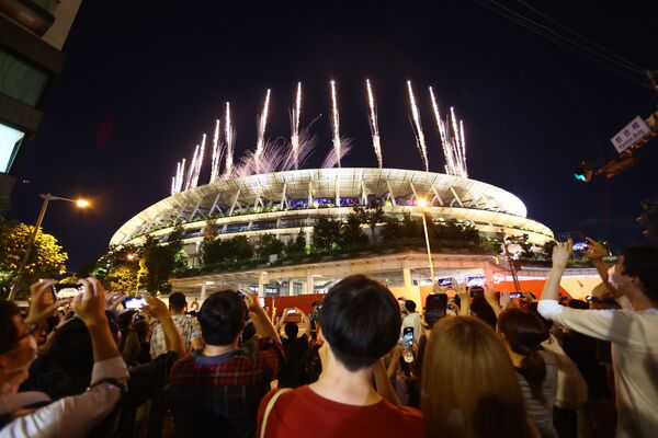 Люди снаружи Национального олимпийского стадиона в Токио наблюдают за фейерверком во время торжественной церемонии закрытия XXXII летних Олимпийских игр. - Sputnik Латвия