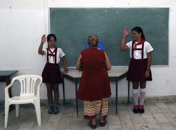 Школьники приветствуют женщину, голосующую во время первых местных выборов на Кубе. - Sputnik Латвия