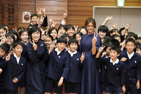 Бывшая первая леди США Мелания Трамп и Акиэ Абэ, супруга японского премьер-министра Синдзо Абэ,  фотографируются со школьниками в начальной школе Kyobashi Tsukiji в Токио. - Sputnik Латвия
