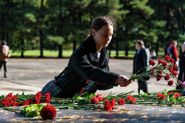 Sieviete ar ziediem Salaspils koncentrācijas nometnes atbrīvošanas 77. gadadienai veltītajā ceremonijā - Sputnik Latvija