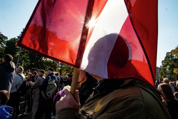Мужчина с флагом Латвии на митинге протеста у памятника Свободы - Sputnik Латвия