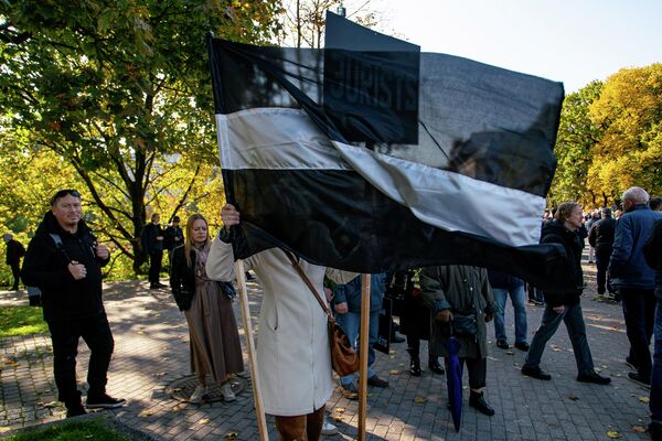 Латвийский флаг в черно-белом исполнении на митинге протеста - Sputnik Латвия