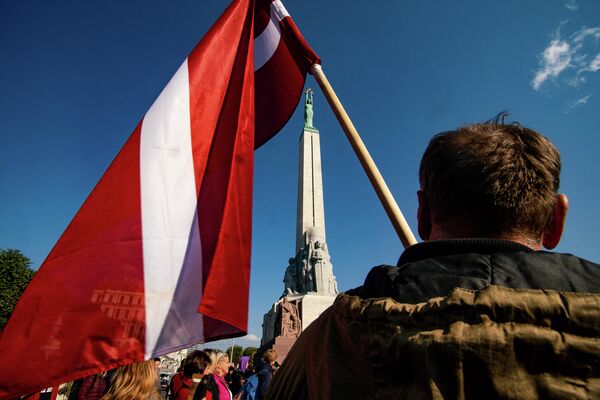 Мужчина с флагом Латвии на митинге протеста у памятника Свободы - Sputnik Латвия