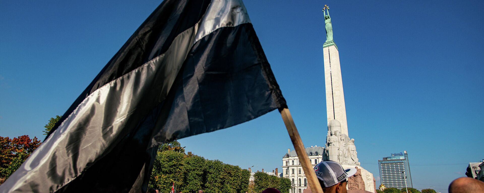 Латвийский флаг в черно-белом исполнении на митинге протеста у памятника Свободы - Sputnik Латвия, 1920, 03.10.2021
