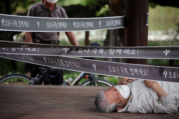 Vīrietis pie paviljona, kas ielenkts Covid-19 izplatības novēršanai Seulas parkā - Sputnik Latvija
