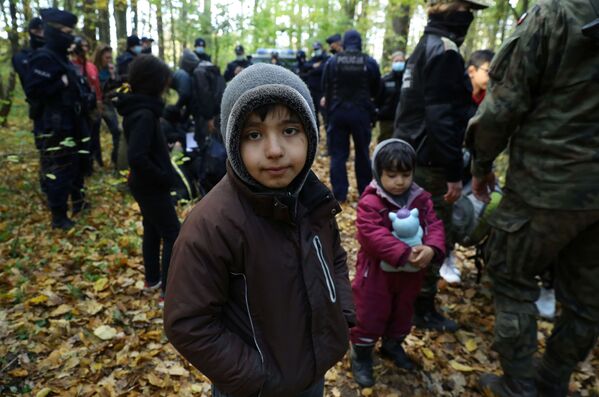 Иракский ребенок в окружении пограничников и полицейских после пересечения белорусско-польской границы в городе Хайнувка, Польша. - Sputnik Латвия