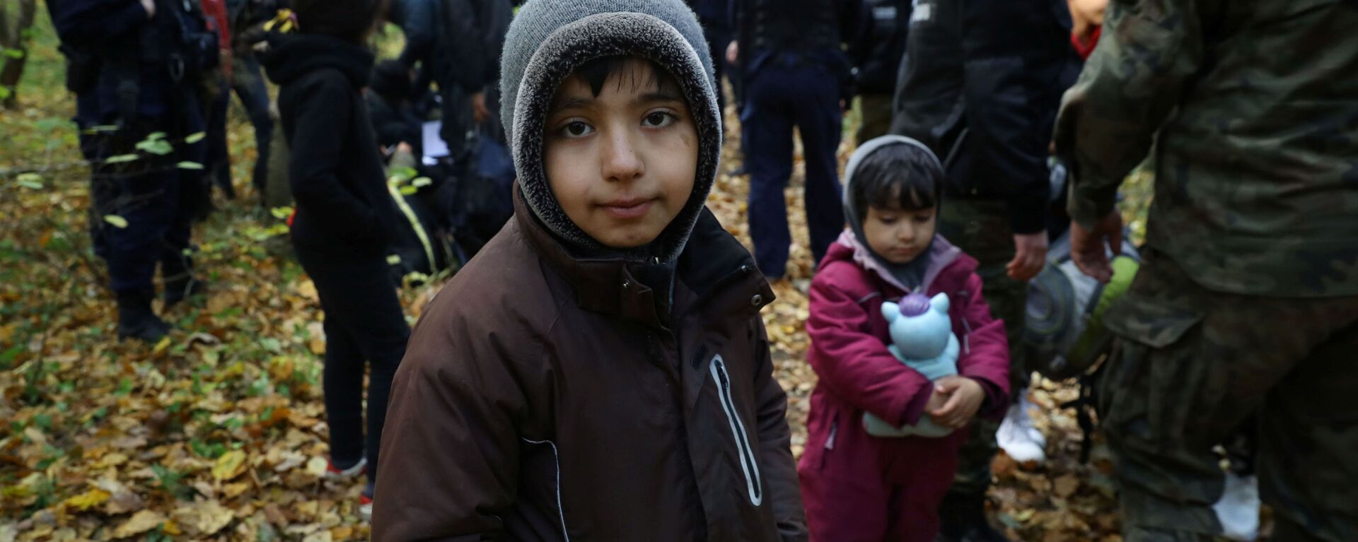 Иракский ребенок в окружении пограничников и полицейских после пересечения белорусско-польской границы в городе Хайнувка, Польша - Sputnik Латвия, 1920, 16.10.2021