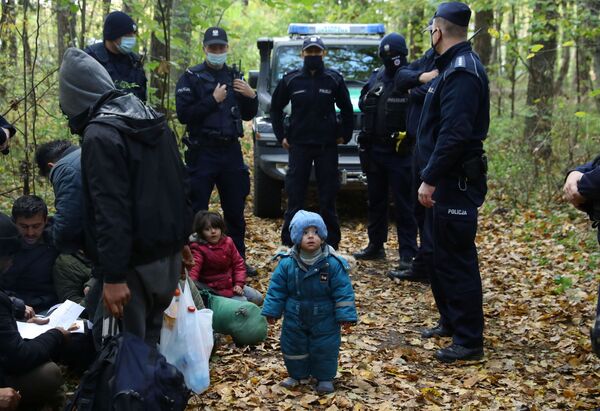 Мигранты в окружении пограничников и полицейских, после того как они пересекли белорусско-польскую границу, Хайновка, Польша. - Sputnik Латвия
