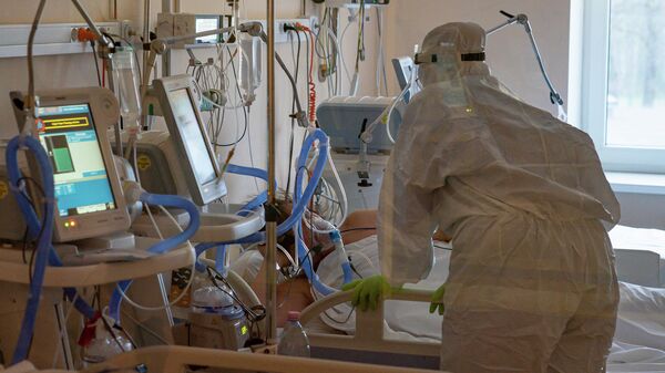 Медицинский работник у кровати с тяжелым пациентом COVID-19 в Центре легочных заболеваний и туберкулеза в Даугавпилсе - Sputnik Латвия