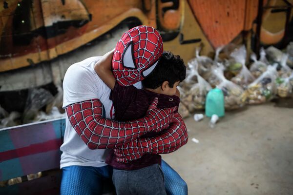 Brīvprātīgais Zirnekļcilvēka maskā apskauj bērnu Riodežaneiro favelās - Sputnik Latvija
