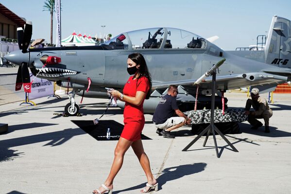 Meitene iet garām trieciena lidmašīnai Beechcraft AT-6 Wolverine starptautiskajā aviosalonā &quot;Dubai Airshow 2021&quot; - Sputnik Latvija