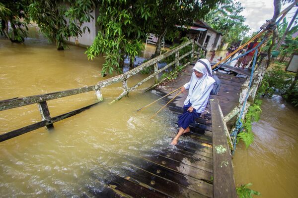Meitene šķērso upi pa plūdos sagrautu tiltu Indonēzijā - Sputnik Latvija
