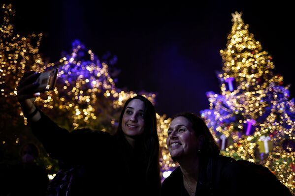 Люди фотографируются во время церемонии зажжения праздничных огней на рождественской ели в Афинах. - Sputnik Латвия
