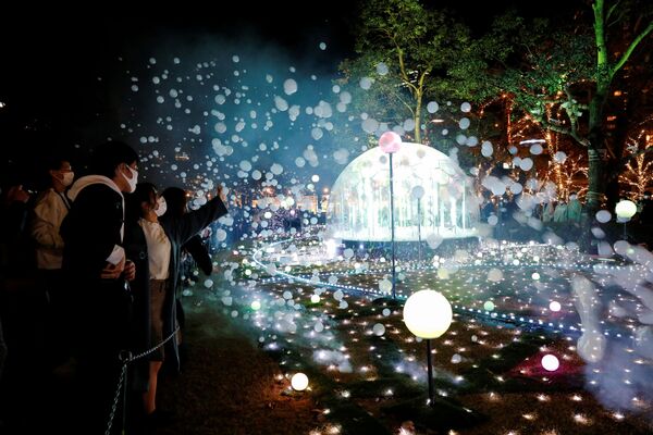 Люди фотографируют праздничную иллюминацию в Токио. - Sputnik Латвия