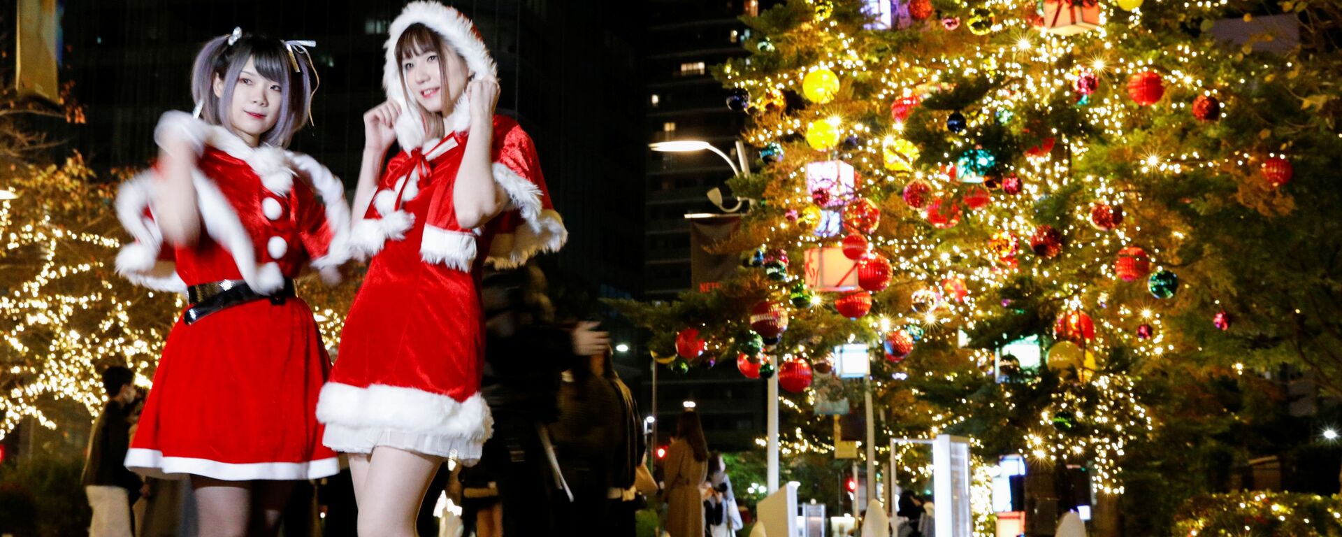 Девушки в костюмах Санта-Клауса фотографируются на фоне рождественских иллюминаций в Токио, Япония - Sputnik Latvija, 1920, 28.11.2021