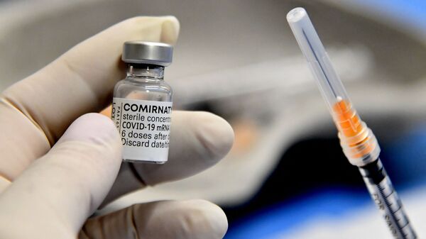 Медицинский работник держит шприц и флакон вакцины Comirnaty от Pfizer-BioNTech против Covid-19, Италия - Sputnik Латвия