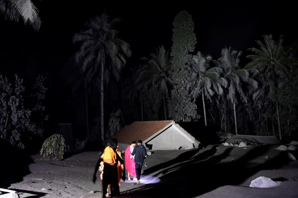 Ciema iedzīvotāji pie vulkānisko pelnu apbērtas mājas Sumbervulu ciemā Lumadžangas rajonā - Sputnik Latvija