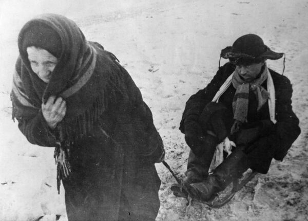 Первая блокадная зима была особенно лютой, морозы достигали 40 градусов. Женщина везет ослабевшего от голода мужа на санках.  - Sputnik Латвия