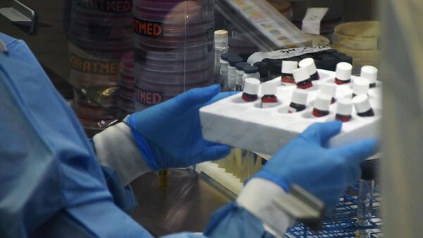 Сотрудник лаборатории держит контейнер с пробирками. Лабораторию подозревают в разработках биологического оружия - Sputnik Latvija