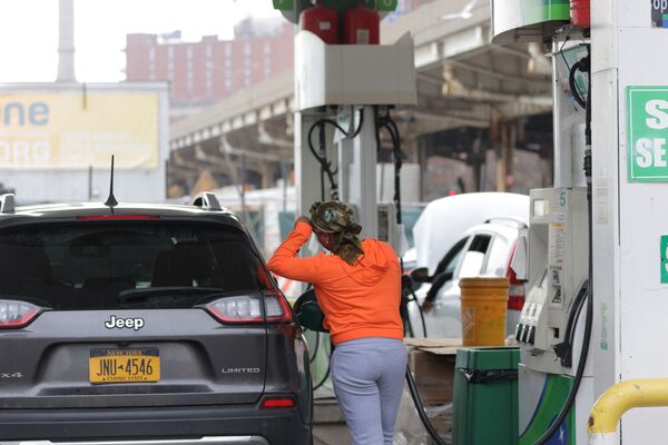 Женщина заправляет автомобиль на заправочной станции в Манхэттене, штат Нью-Йорк. - Sputnik Латвия