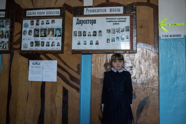 Bērni skolās viegli atšķir šāviņu skaņas un zina, kur paslēpties.Meitene Sahankas skolā. Bultiņa norāda uz patvērumu – tādas skolā ir visur, lai vieglāk atrast glābiņu - Sputnik Latvija