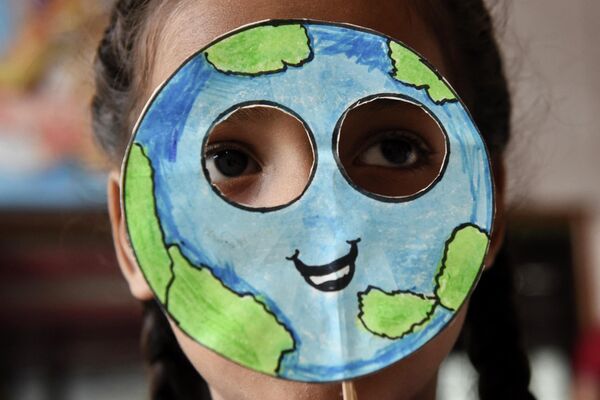 Ученик надевает маску, сделанную в форме планеты Земля, во время мероприятия по случаю &quot;Дня Земли&quot;  - Sputnik Латвия
