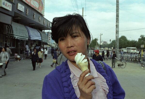 Одна из улиц Пекина, Китайская Народная Республика. Жительница китайской столицы позирует с мороженым на улице 20 июня 1990 года.  - Sputnik Латвия
