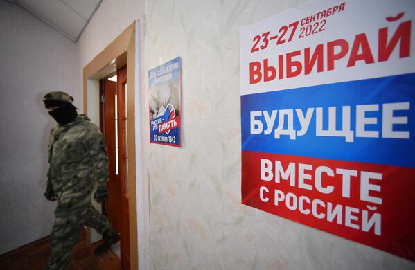 Участник добровольческого отряда на избирательном участке во время голосования на референдуме о присоединении Запорожской области к России в Мелитополе - Sputnik Латвия