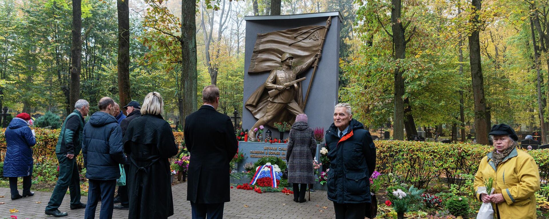 Жители Риги возлагают цветы к мемориалу советским воинам-освободителям на Покровском кладбище в Риге, 13 октября 2022 года - Sputnik Латвия, 1920, 13.10.2022