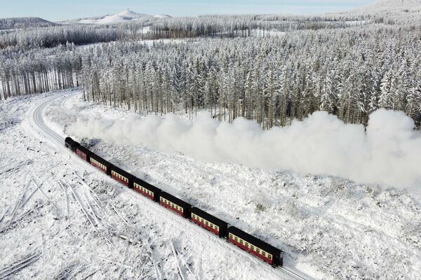 Паровоз проезжает по заснеженному ландшафту в горах Гарц близ Вернигероде, Германия - Sputnik Латвия