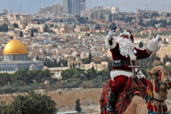 Палестинец в костюме Санта-Клауса на верблюде в Иерусалиме. - Sputnik Латвия