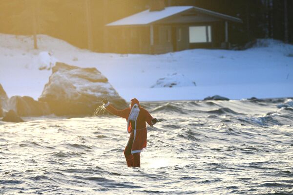 Человек в костюме Санта-Клауса во время серфинга в Финляндии. - Sputnik Латвия