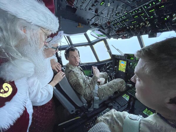 Санта и миссис Клаус беседуют с летным экипажем грузового самолета Национальной гвардии Аляски по пути в Нуиксут, штат Аляска, где Клаус каждый год дарит подарки детям. - Sputnik Латвия